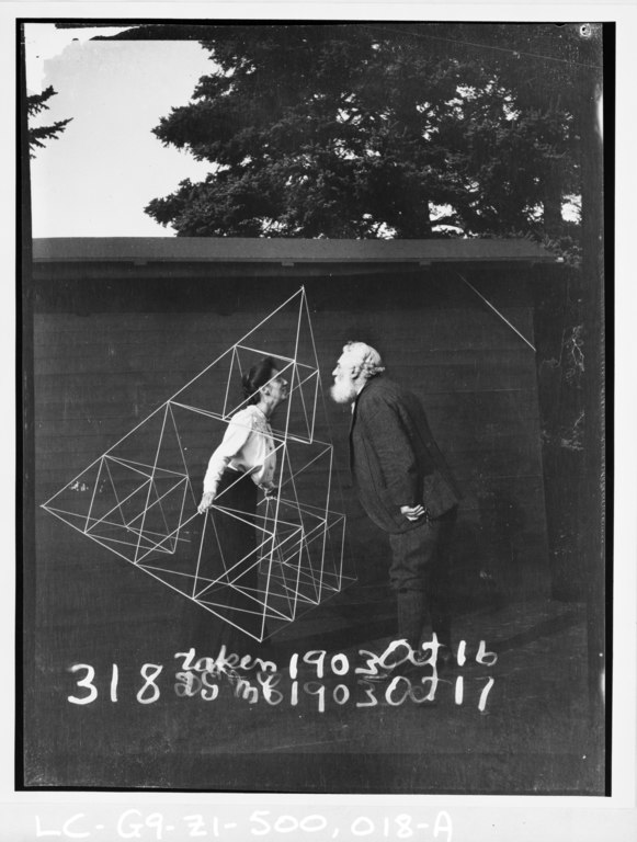 Mabel Bell and Alexander Graham Bell kissing in a Sierpiński tetrahedron kite frame, from https://commons.wikimedia.org/wiki/File:Alexander_Graham_Bell_facing_his_wife,_Mabel_Hubbard_Gardiner_Bell,_who_is_standing_in_a_tetrahedral_kite,_Baddeck,_Nova_Scotia.tif