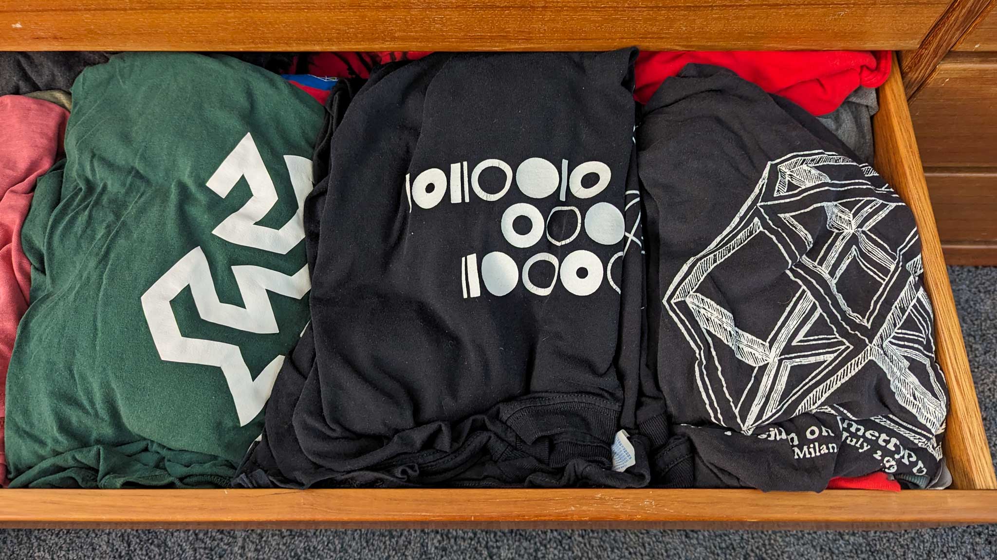 T-shirts in an open dresser drawer, including a Computer History Museum shirt showing the binary ASCII code for "chm"